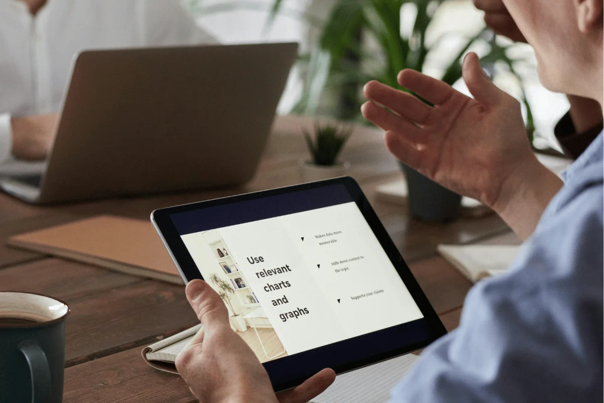 Person presenting data on a tablet showing charts and graphs.