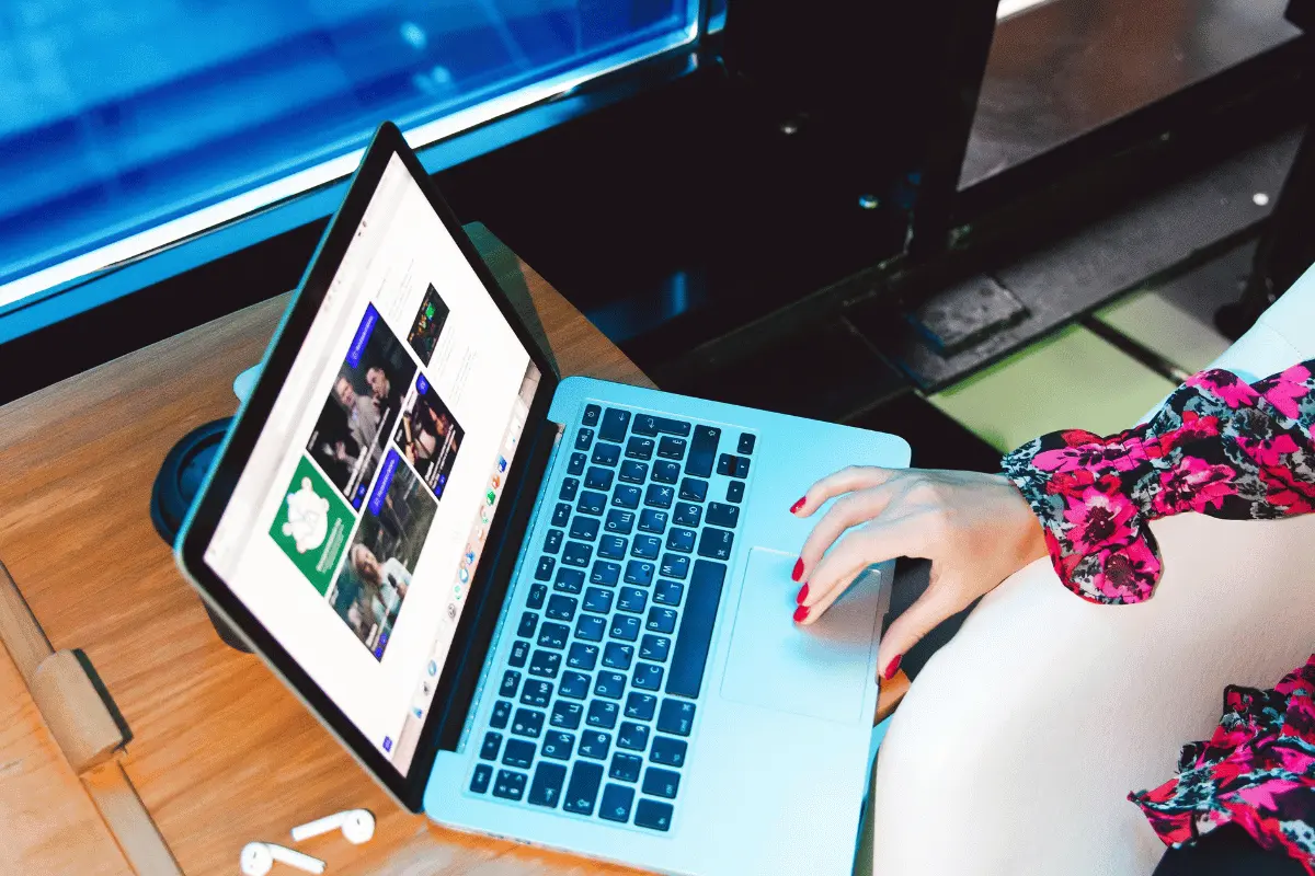 Person using a laptop to browse a website, with earphones placed on the desk.