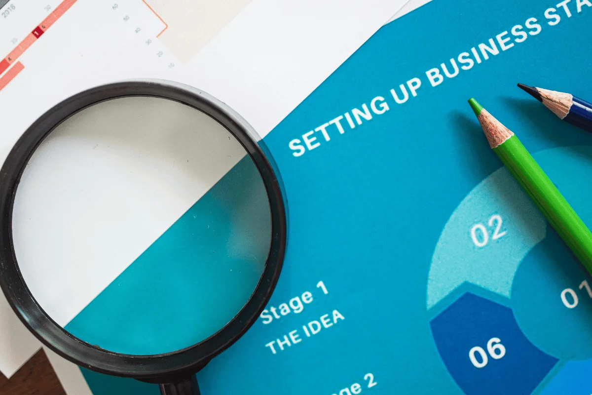 Close-up of business strategy document with magnifying glass and pencils.