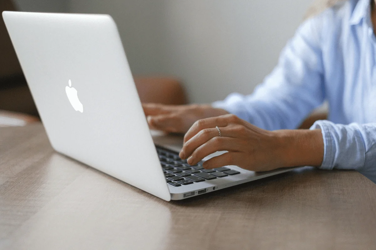 Apple MacBook in use, showing user’s hands and keyboard.