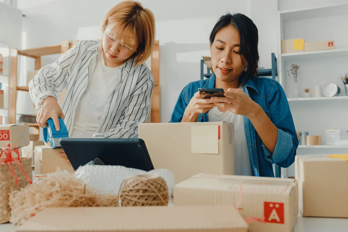 Two women preparing eCommerce packages for shipment.