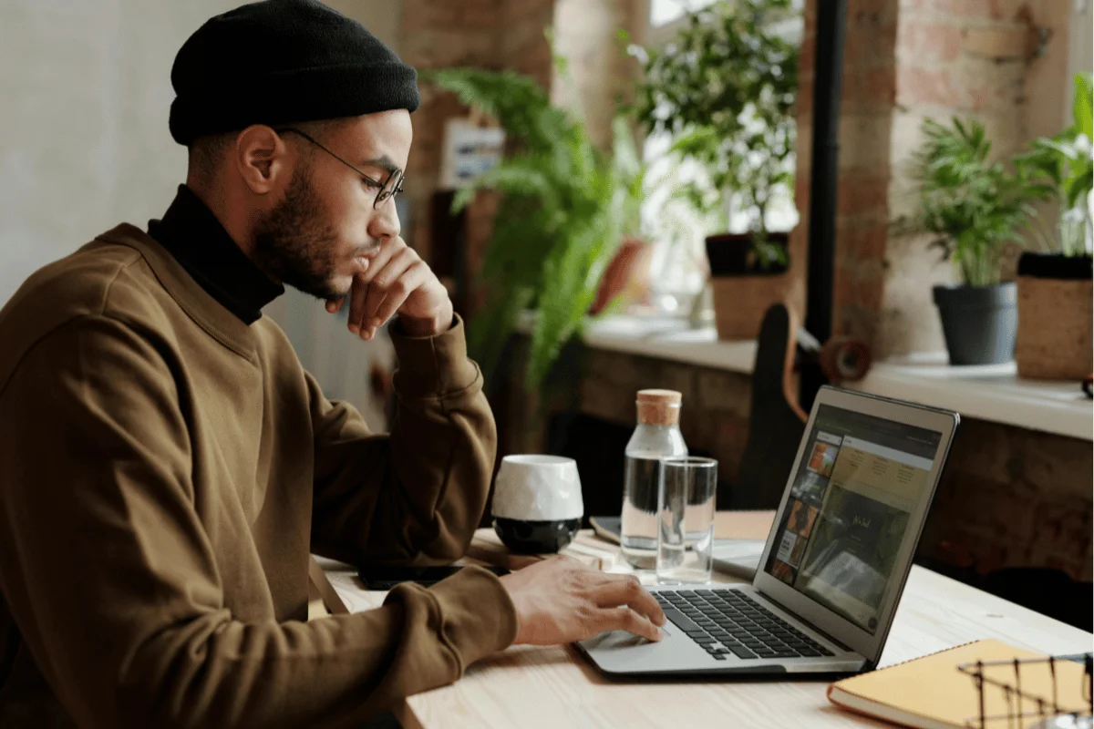 Person in a modern workspace with a laptop and potted plants.