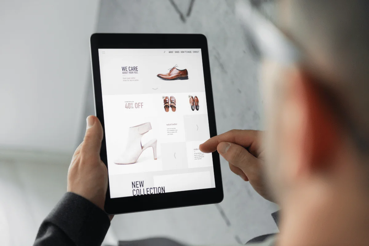 A close-up of someone shopping online for shoes, viewing a new collection on a tablet.