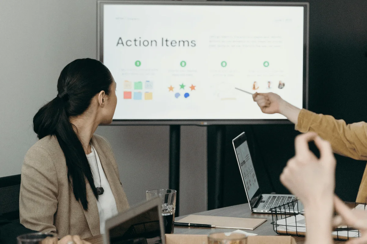 Presenter pointing to screen with project action steps.