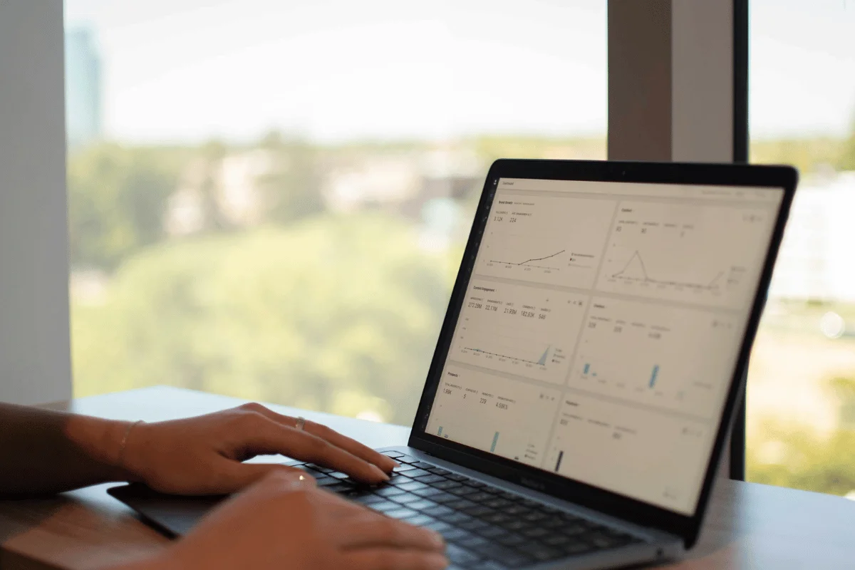 Person analyzing business analytics dashboard on a laptop near a window.