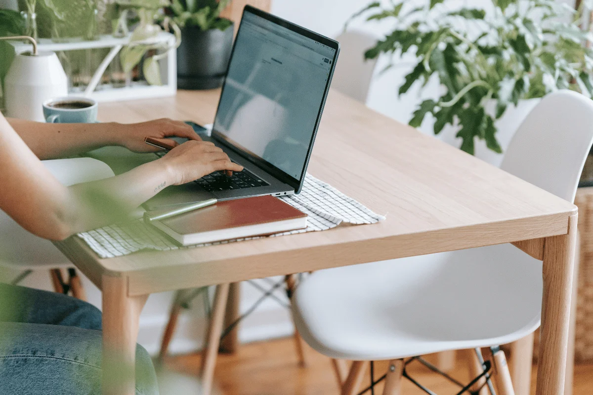 Person working on laptop at a clean, minimalist wooden desk.